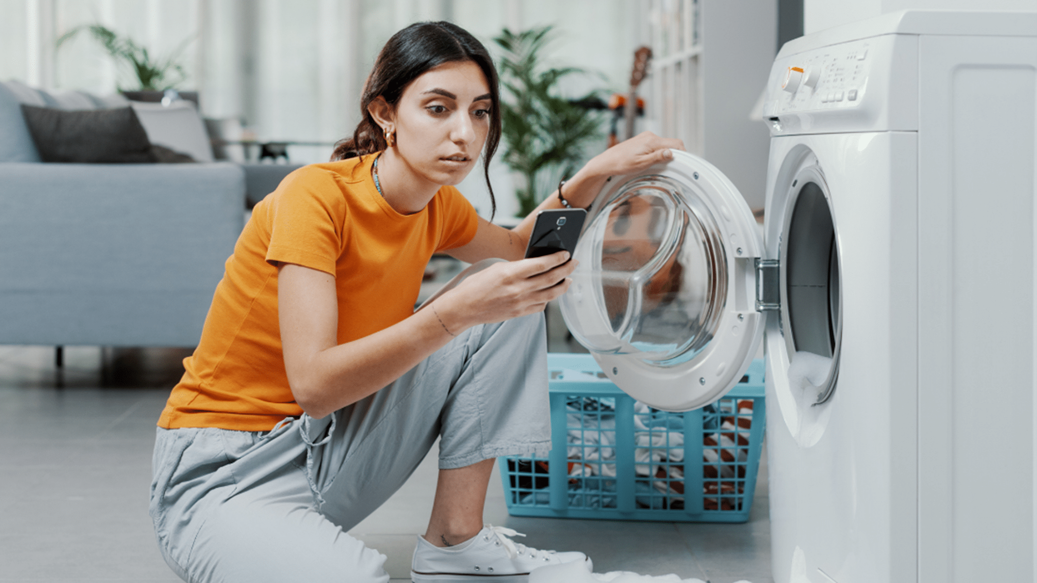 Girl looking on phone while doing laundry